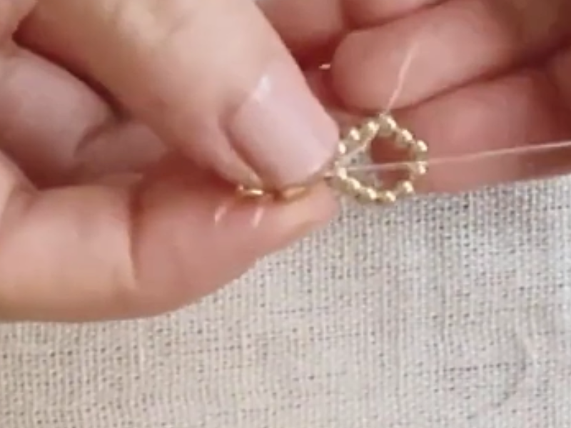 coloca una argolla y vuelve a pasar los hilos por el extremo contrario del cuadrado dorado